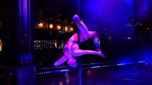 Dancer in tie dye outfit takes a spin on the pole.